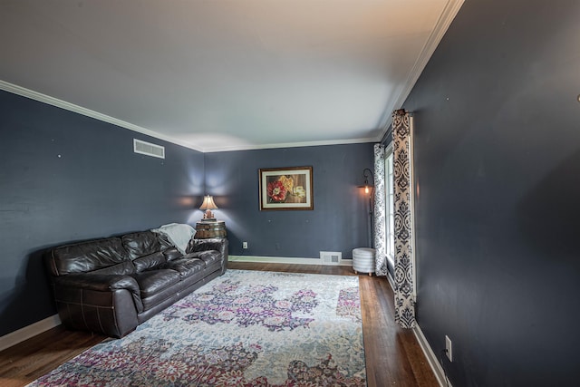 living area featuring visible vents, baseboards, wood finished floors, and crown molding