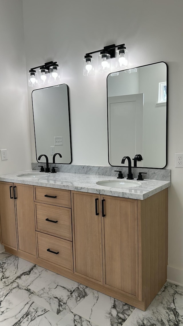 full bath featuring double vanity, marble finish floor, and a sink