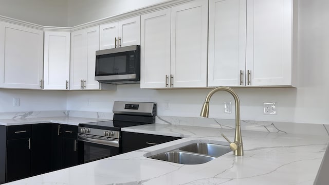 kitchen featuring a sink, dark cabinets, white cabinetry, and stainless steel appliances