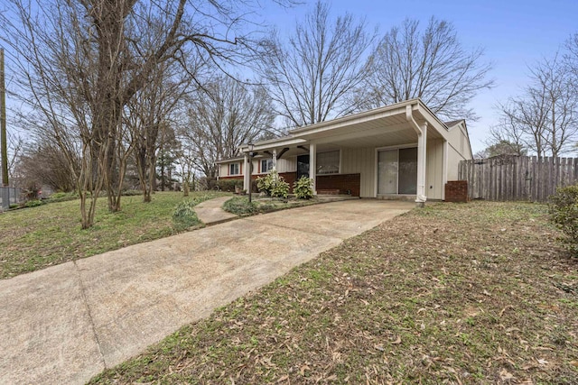 ranch-style house with a carport, concrete driveway, fence, and brick siding