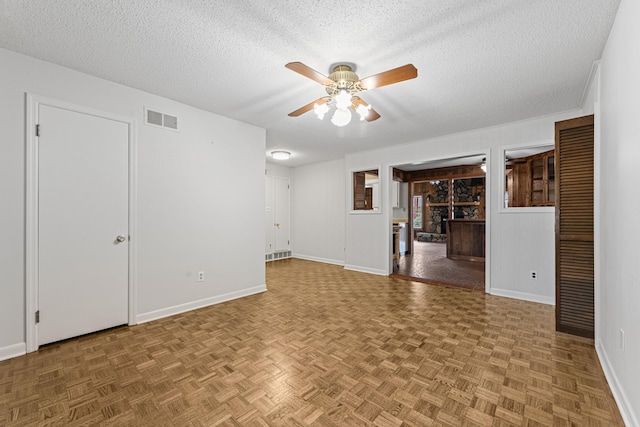 unfurnished living room featuring baseboards, visible vents, a textured ceiling, and ceiling fan