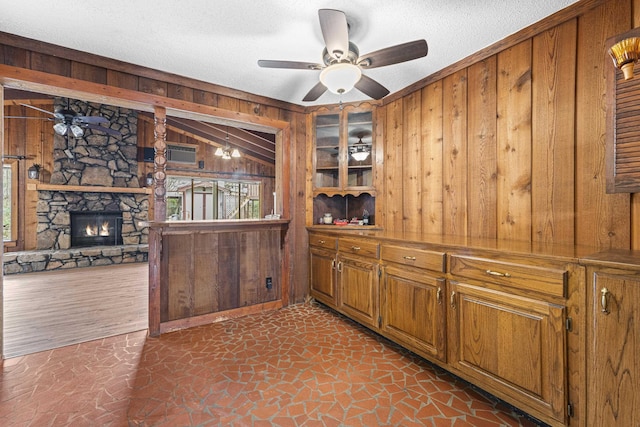 kitchen featuring vaulted ceiling, a healthy amount of sunlight, brown cabinets, and wood walls