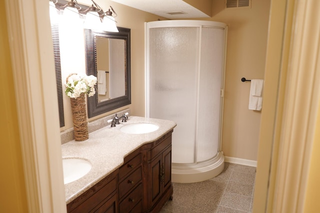 bathroom featuring visible vents, a sink, a shower stall, double vanity, and baseboards