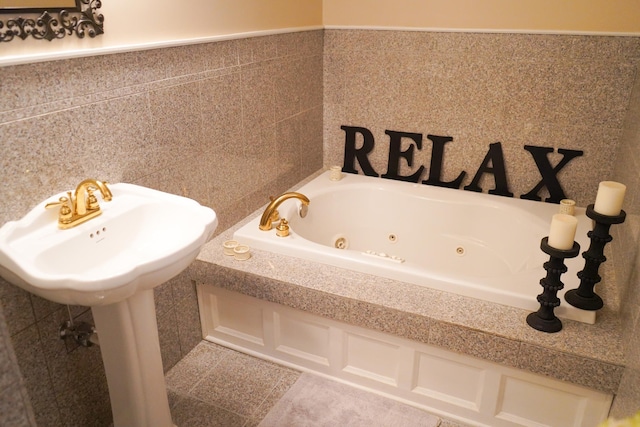 bathroom with tile patterned flooring, a wainscoted wall, tile walls, and a whirlpool tub