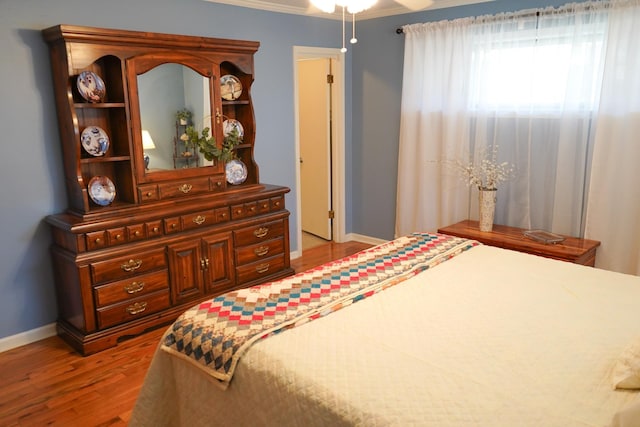 bedroom featuring ornamental molding, a ceiling fan, baseboards, and wood finished floors