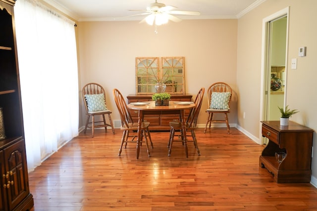 dining area featuring crown molding, light wood-style flooring, a ceiling fan, and baseboards