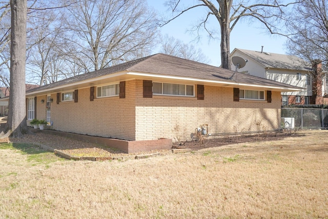 exterior space featuring brick siding, a lawn, and fence