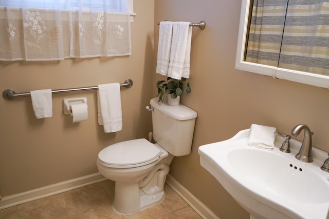 bathroom featuring a sink, baseboards, toilet, and tile patterned flooring