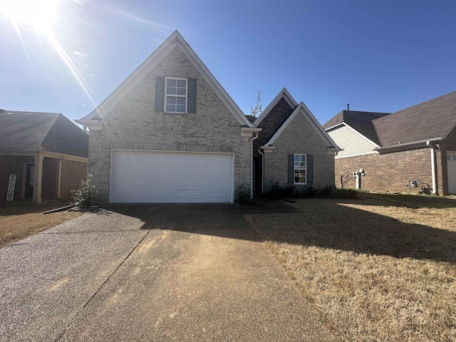 traditional-style home featuring a front lawn, an attached garage, brick siding, and driveway