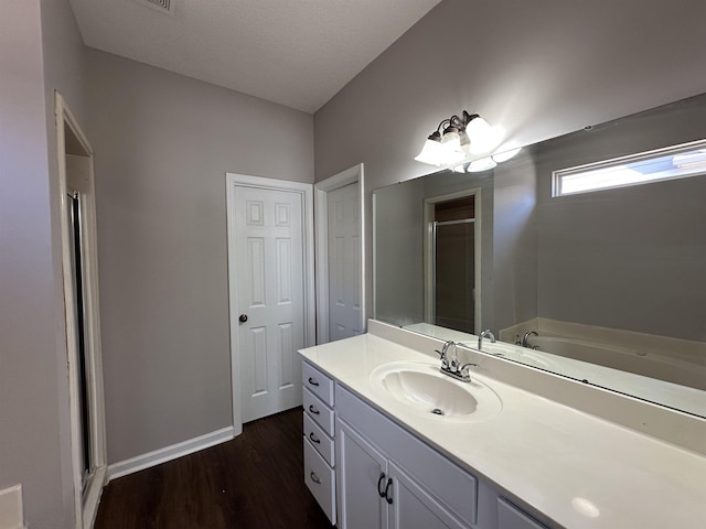 full bathroom featuring a stall shower, vanity, baseboards, and wood finished floors