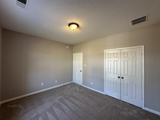 unfurnished bedroom featuring baseboards, visible vents, a textured ceiling, and carpet