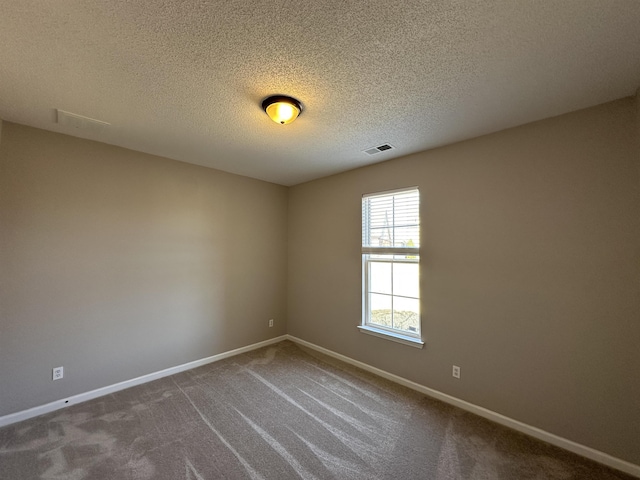 empty room featuring baseboards, visible vents, dark colored carpet, and a textured ceiling