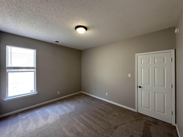 unfurnished room with visible vents, carpet flooring, a textured ceiling, and baseboards