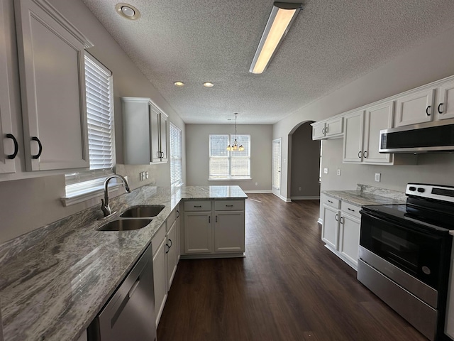 kitchen with a notable chandelier, a sink, light stone counters, appliances with stainless steel finishes, and a peninsula