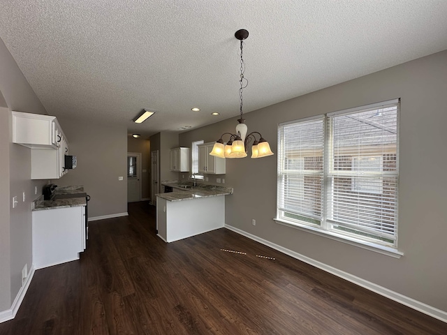 kitchen featuring baseboards, a sink, dark wood-type flooring, white cabinetry, and a notable chandelier