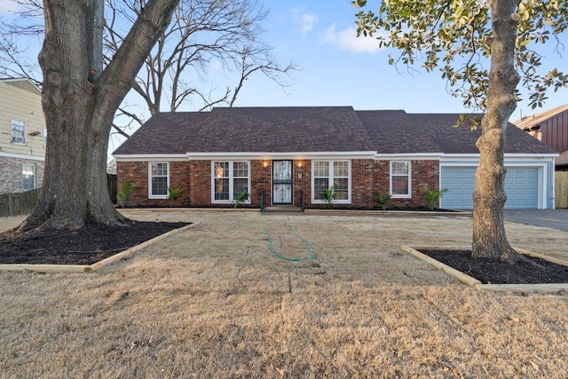 ranch-style home featuring a garage, brick siding, roof with shingles, and a front yard