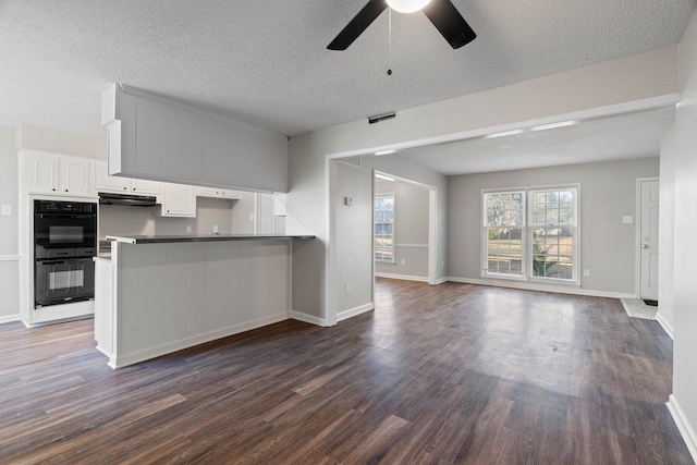 kitchen with dark wood-type flooring, a ceiling fan, dobule oven black, open floor plan, and white cabinets