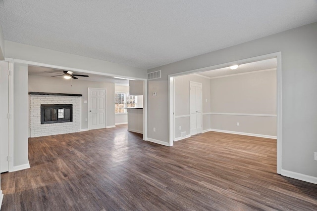 unfurnished living room with dark wood-style floors, baseboards, a ceiling fan, visible vents, and a textured ceiling