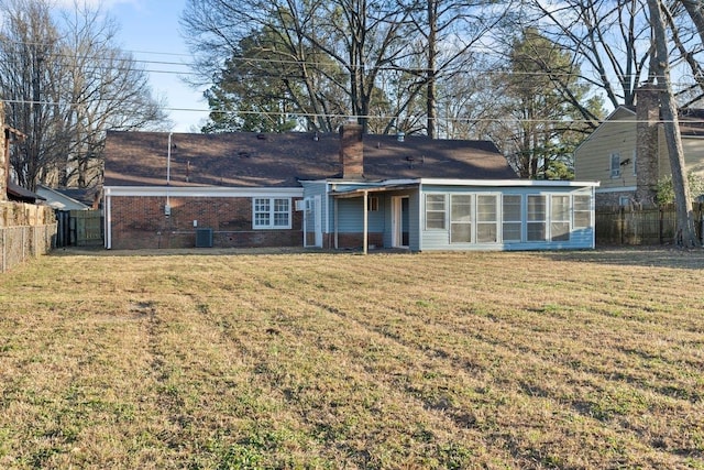 rear view of property with fence, a lawn, a chimney, and a sunroom