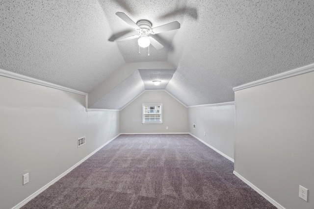 bonus room with a ceiling fan, visible vents, carpet floors, lofted ceiling, and a textured ceiling