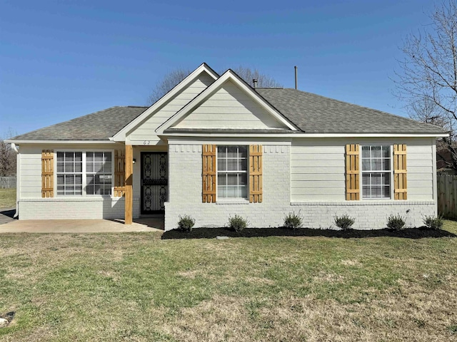 ranch-style home with a patio area, brick siding, a front lawn, and a shingled roof