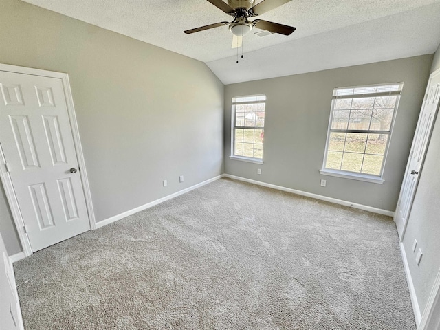 unfurnished bedroom with baseboards, ceiling fan, lofted ceiling, carpet floors, and a textured ceiling