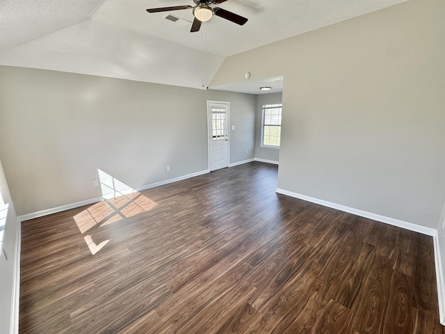 empty room with dark wood finished floors, lofted ceiling, a ceiling fan, and baseboards