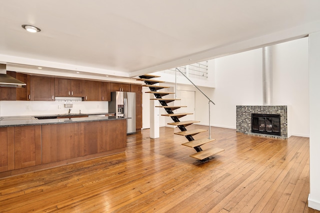 unfurnished living room featuring light wood finished floors, a fireplace, and stairs