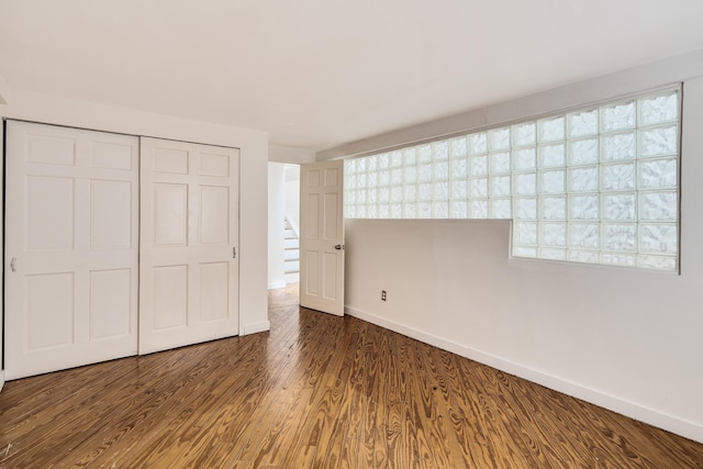 unfurnished bedroom featuring a closet, baseboards, and wood finished floors