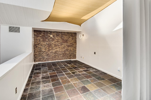 empty room with visible vents, brick wall, wood ceiling, and baseboards