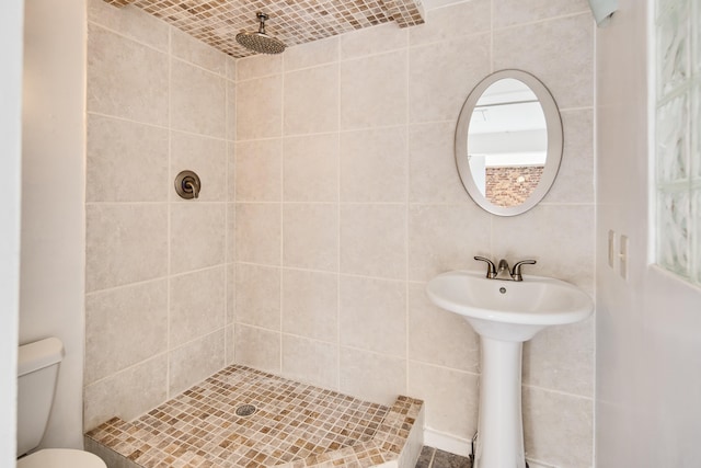 full bathroom featuring toilet, tiled shower, and a sink