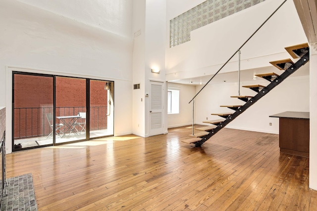 entryway featuring hardwood / wood-style floors, stairway, visible vents, baseboards, and a towering ceiling