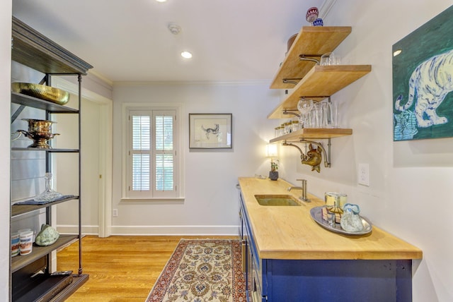 office space with light wood-style flooring, a sink, wet bar, crown molding, and baseboards