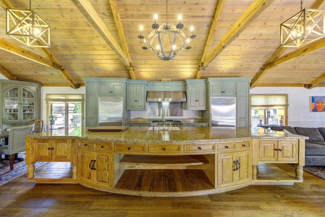 kitchen featuring built in refrigerator, stainless steel refrigerator, a sink, lofted ceiling with beams, and wall chimney range hood