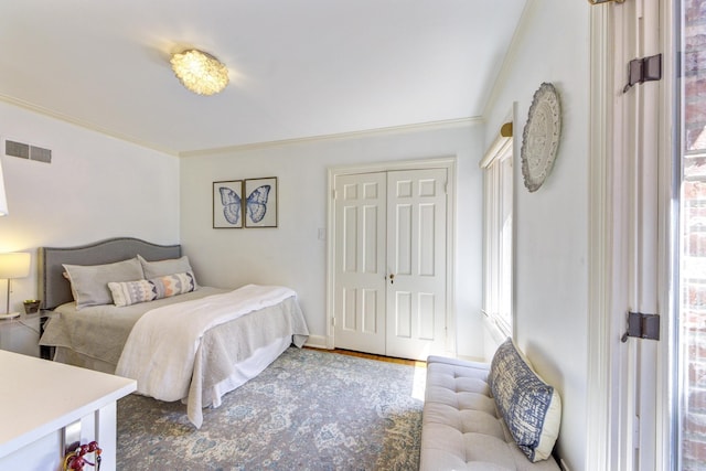 bedroom with a closet, visible vents, crown molding, and wood finished floors