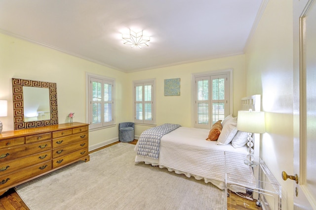 bedroom with wood finished floors, baseboards, and ornamental molding