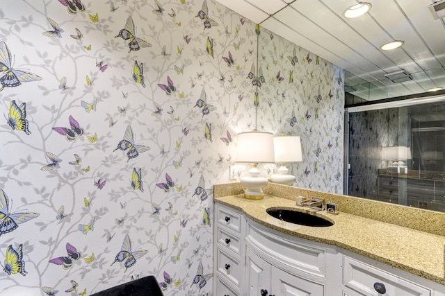 bathroom with a shower with door, recessed lighting, vanity, and wallpapered walls