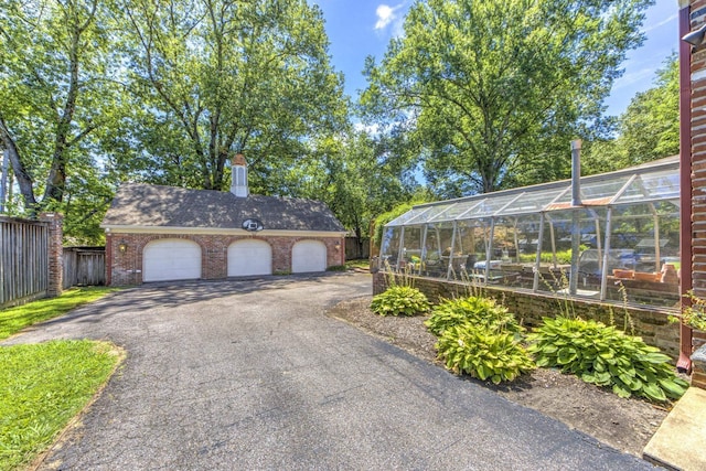 garage featuring aphalt driveway and fence