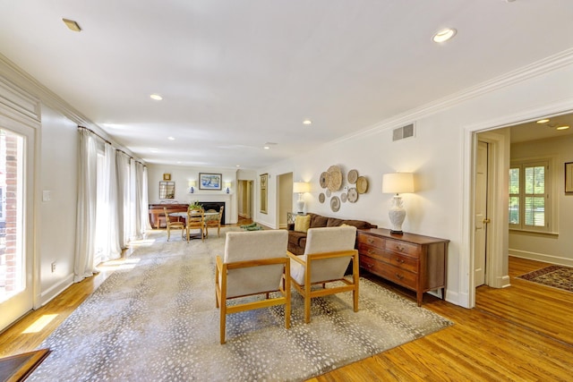 sitting room with visible vents, crown molding, baseboards, recessed lighting, and light wood-style floors