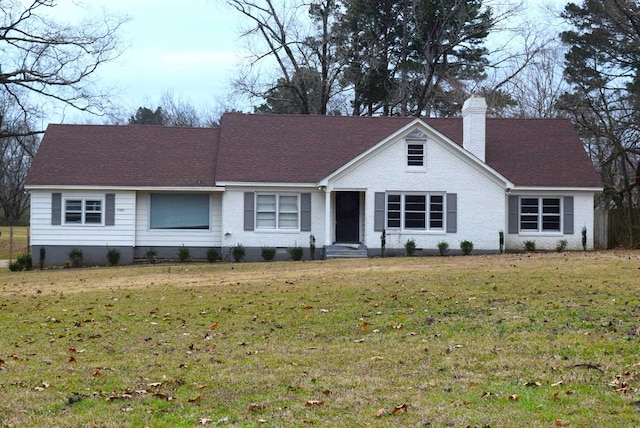 ranch-style home featuring a shingled roof, a front lawn, and a chimney