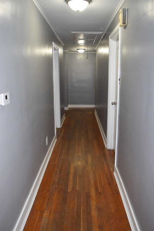 hallway featuring attic access, baseboards, wood-type flooring, and ornamental molding