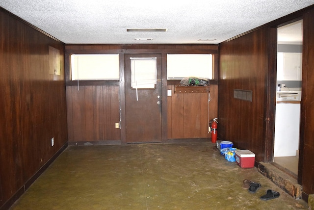 foyer featuring wooden walls and a textured ceiling