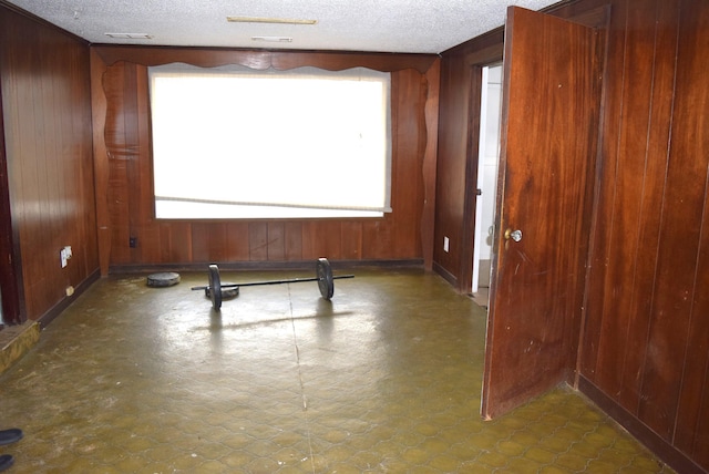 interior space featuring tile patterned floors, wooden walls, and a textured ceiling