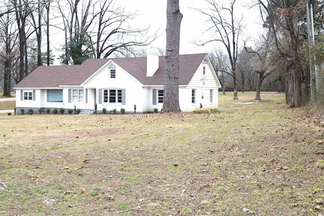 view of front of house featuring roof with shingles, a chimney, and a front yard