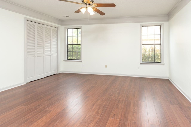 unfurnished bedroom with a closet, dark wood-type flooring, baseboards, and ornamental molding