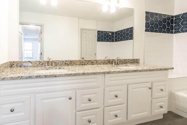 bathroom featuring double vanity, a bath, and a sink