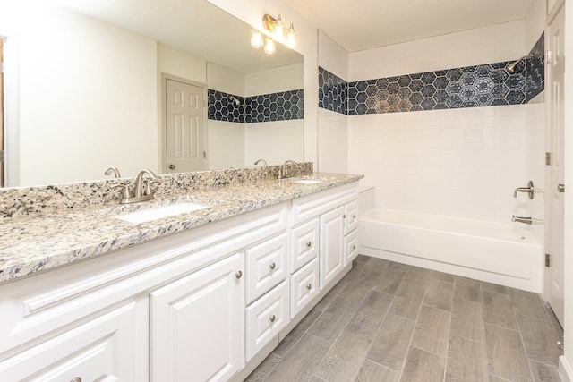 full bathroom featuring double vanity, shower / bathing tub combination, wood tiled floor, and a sink