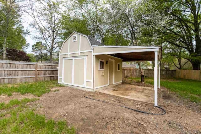 view of shed featuring an attached carport and a fenced backyard