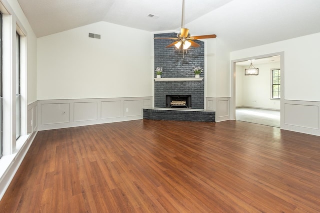 unfurnished living room with visible vents, vaulted ceiling, a fireplace, wood finished floors, and a ceiling fan