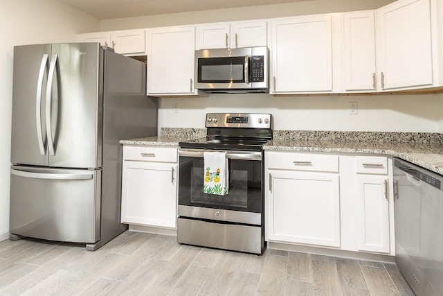 kitchen featuring white cabinetry, stainless steel appliances, and wood finish floors